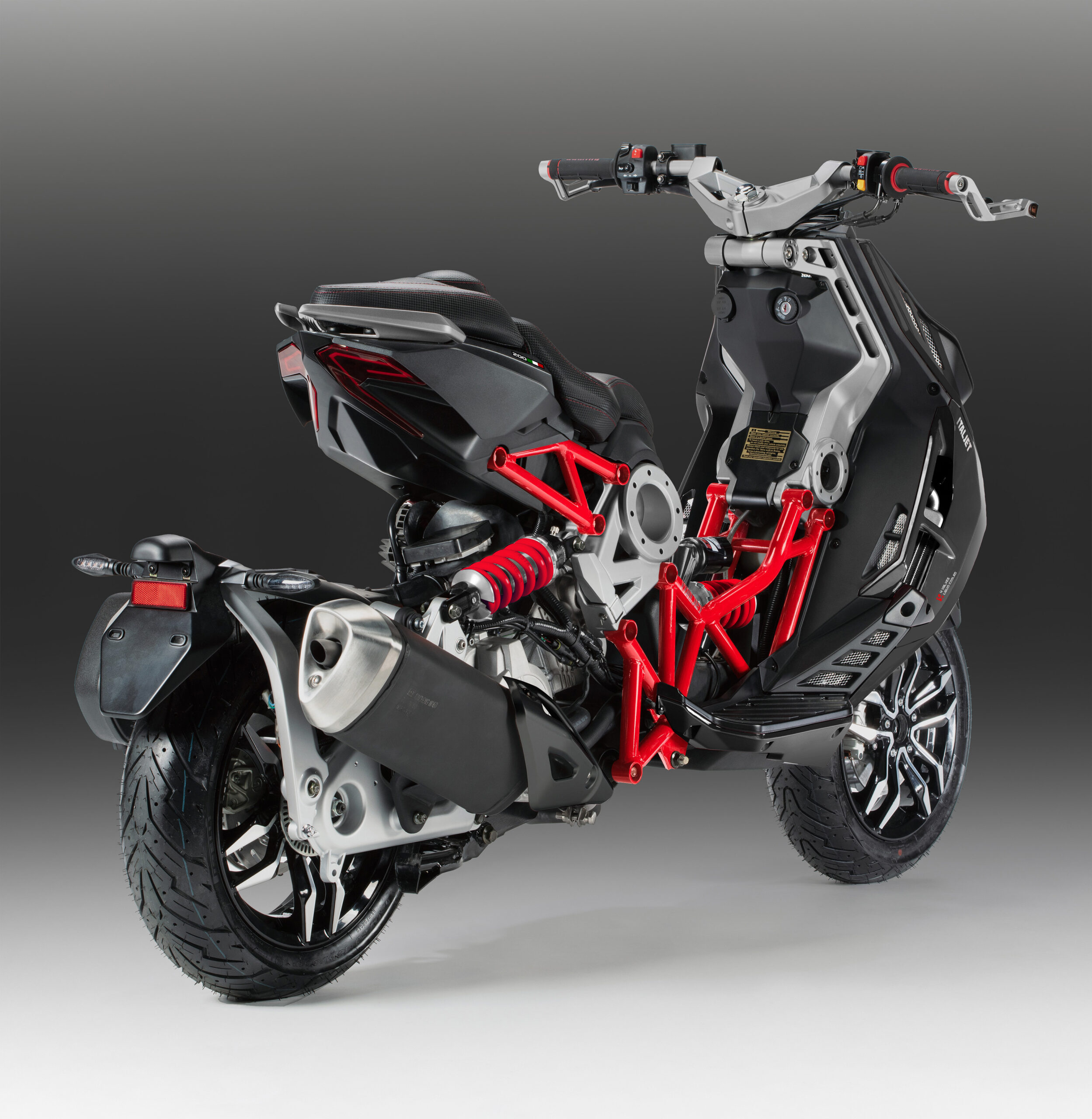 Achter- en zijaanzicht van een moderne, sportieve scooter met een zichtbaar rood frame, gepresenteerd tegen een grijze achtergrond.